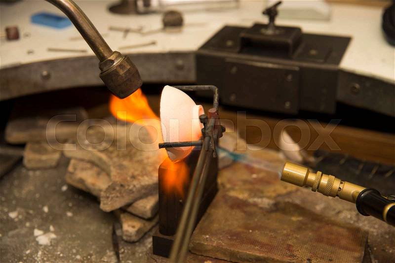 Jeweler melting gold in crucible with gasoline burner , stock photo