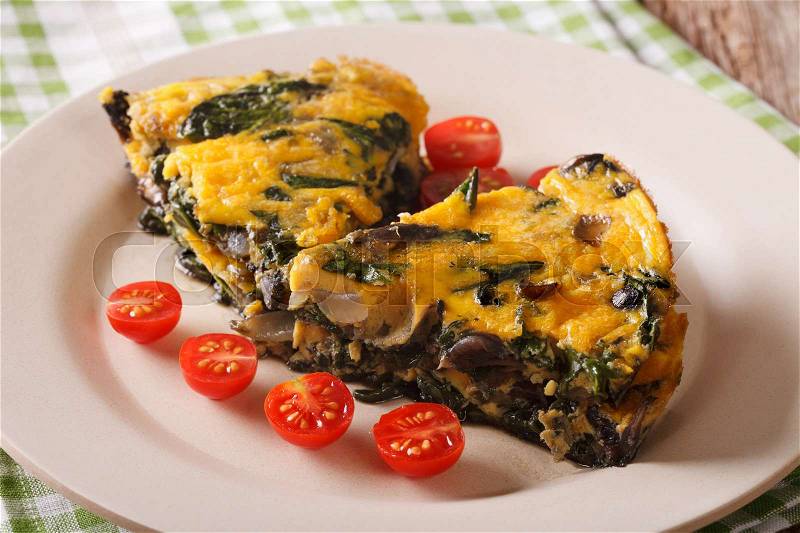 Frittata with spinach, cheddar cheese and mushrooms on a plate on a table close-up. horizontal , stock photo