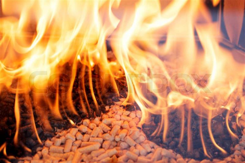 Alternative fuel: Wood pellets burning in a fireplace, stock photo