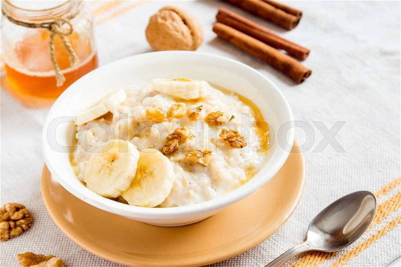 Fresh oatmeal porridge with banana, nuts and honey for healthy breakfast, stock photo