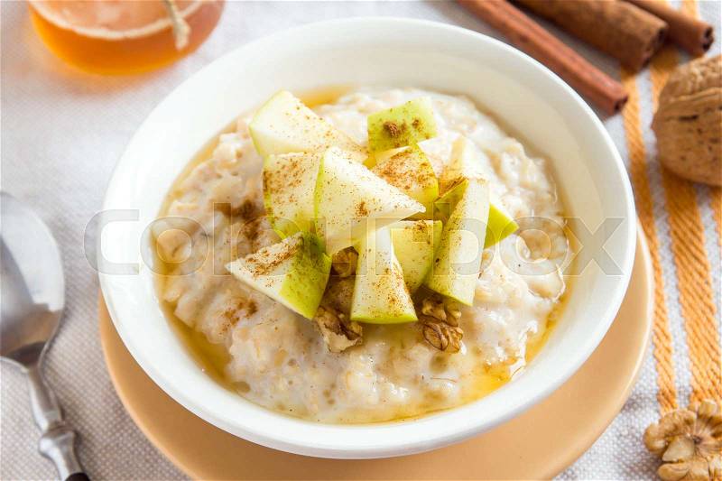 Fresh oatmeal porridge with apples, honey, nuts and cinnamon close up for healthy breakfast, stock photo