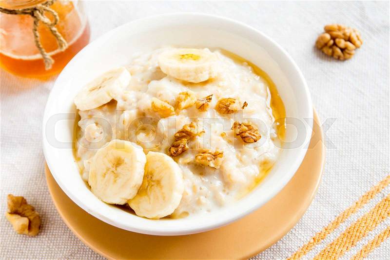 Fresh oatmeal porridge with banana, nuts and honey for healthy breakfast, stock photo