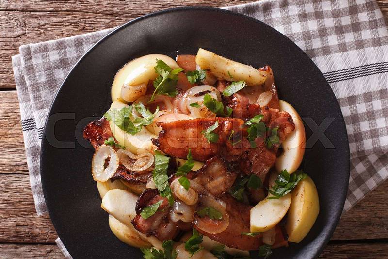 Fried bacon served with onions and apples close-up on a plate. horizontal view from above , stock photo