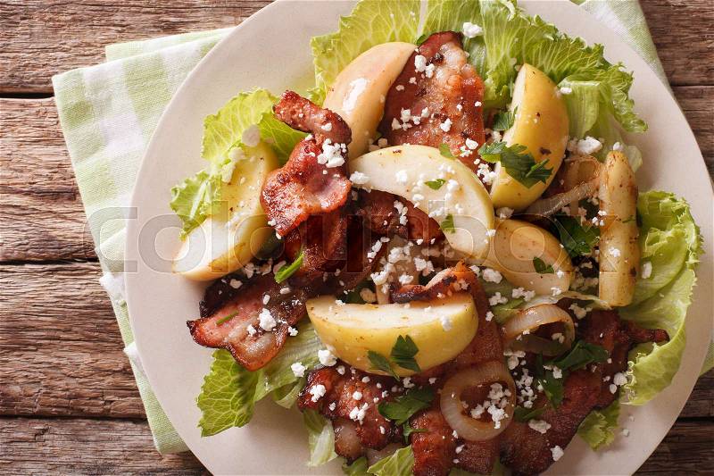 Salad with fried bacon, apple and goat cheese on a plate closeup. Horizontal view from above , stock photo