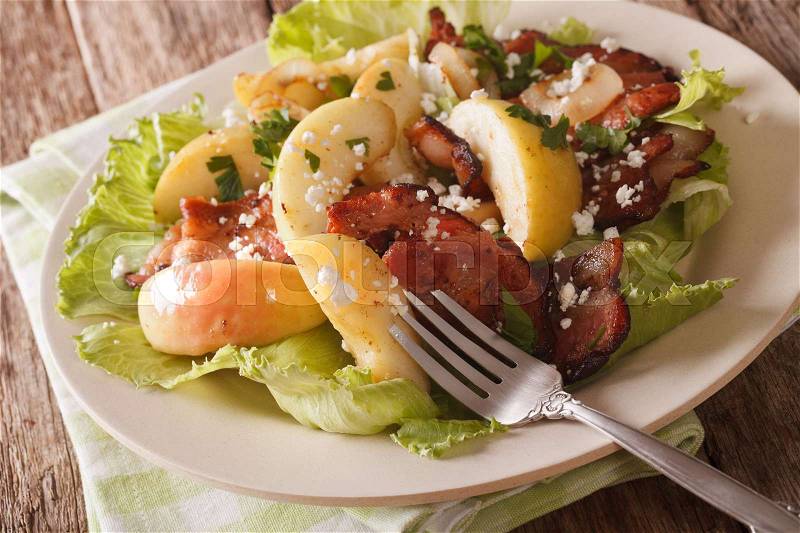 Swedish cuisine salad with fried bacon, onion, green apple and goat cheese close-up on a plate on the table. horizontal , stock photo
