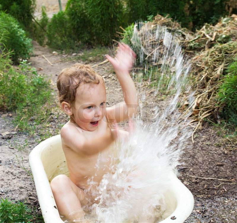 Boy bathing in the tub splashing water, stock photo