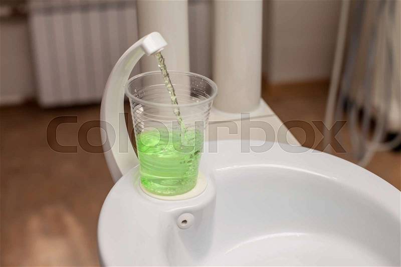 Tooth wash in plastic cup on the sink, stock photo