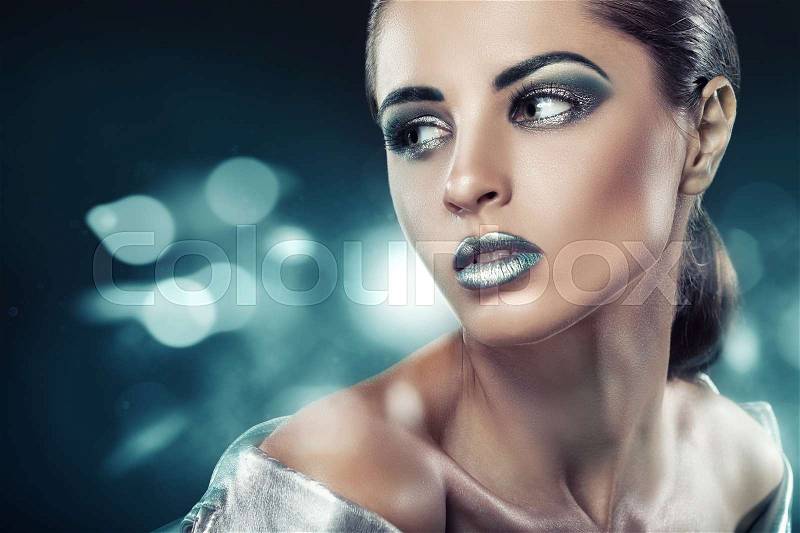 Beautiful young woman with fashion green makeup on bokeh background, stock photo