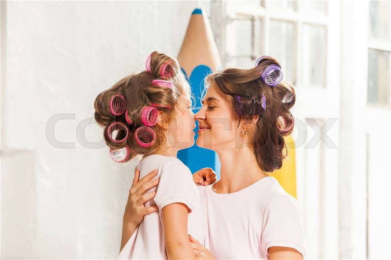 Little smiling girl playing with her mother on white, stock photo