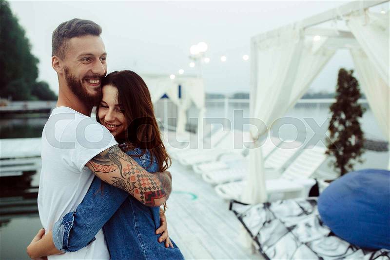 Guy hugging his woman on the pier at the lake, stock photo