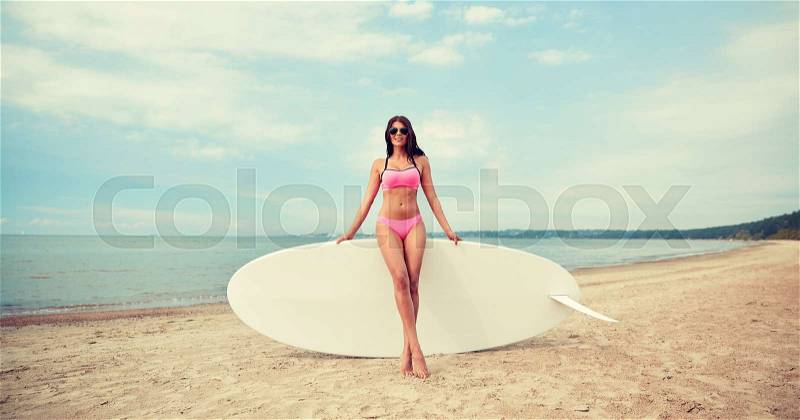 Vacation, surfing, water sport and people concept - young woman in swimsuit with surfboard, windsurf or paddle board on summer beach, stock photo