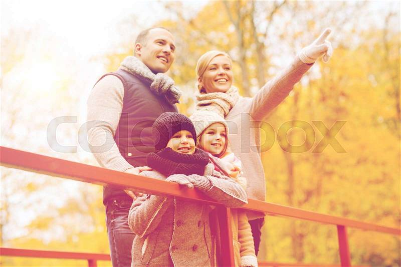 Family, childhood, season and people concept - happy family pointing finger in autumn park, stock photo