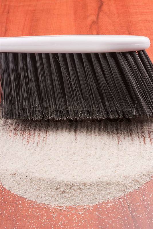 House cleaning, on a floor small sand simulating dust is scattered, stock photo