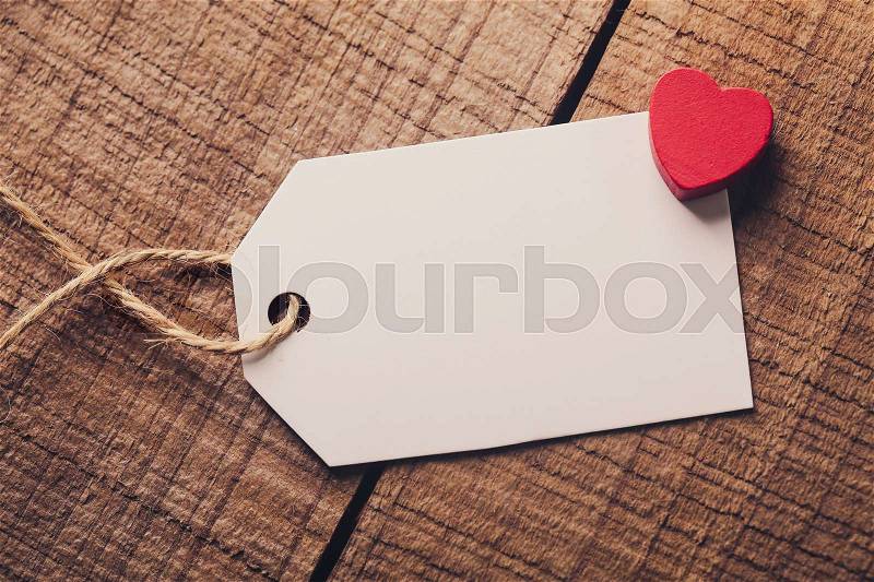 Blank white label is on the wood with red heart aside, stock photo