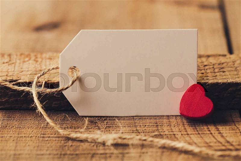 Blank white label is on the wood with red heart aside, stock photo