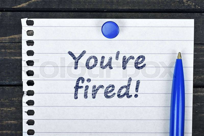 You;\'re fired text on page and pen on wooden table, stock photo