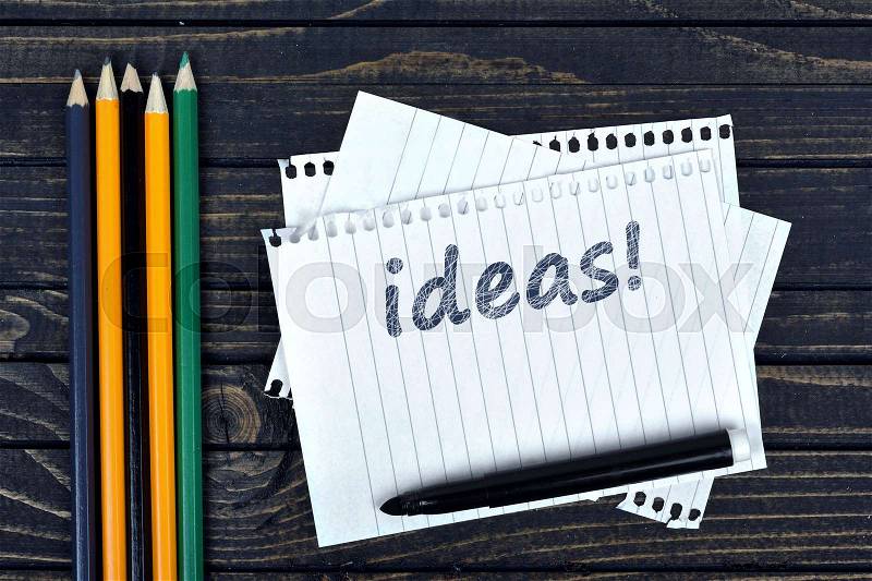 Ideas text on notepad and office tools on wooden table, stock photo