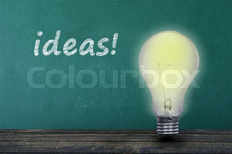 Ideas text on green board and light bulb on table, stock photo