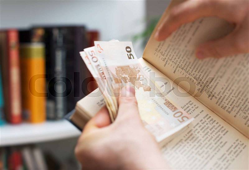 Man hiding money in a book. Secret stash place, stock photo