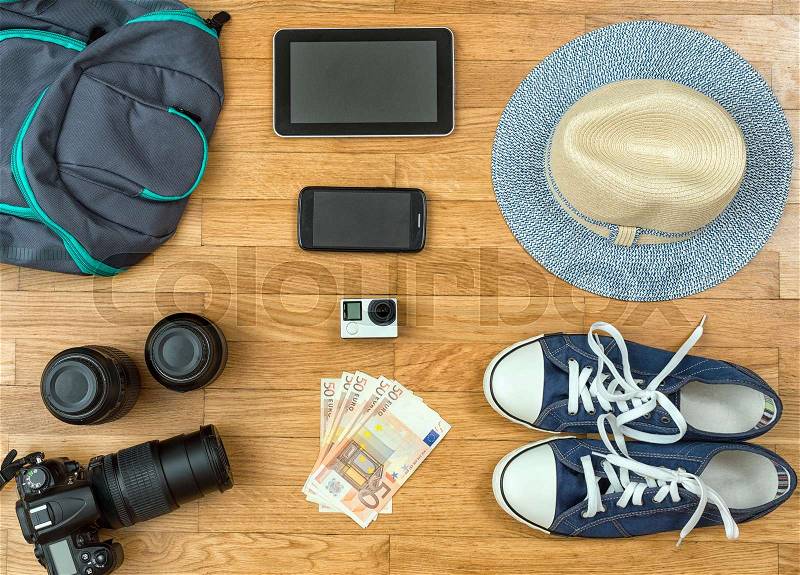 Travel accessories on the floor. Camera, phone, tablet, shoes, hat, money, stock photo