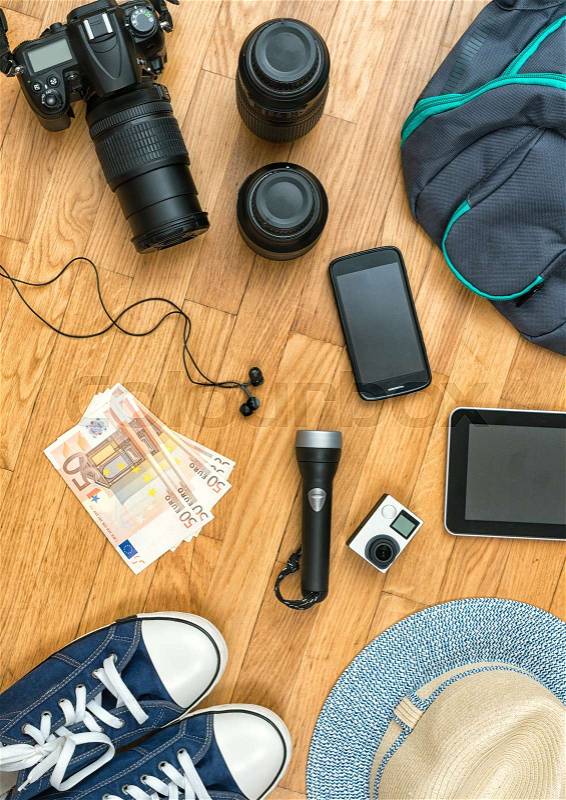 Travel accessories on the floor. Camera, phone, tablet, shoes, hat, money, flashlight, stock photo