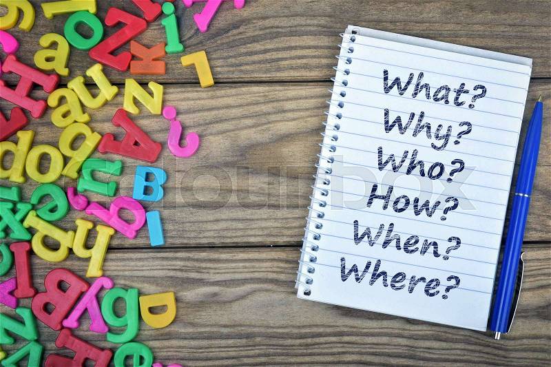 Questions text on notepad and magnetic letters on wooden table, stock photo