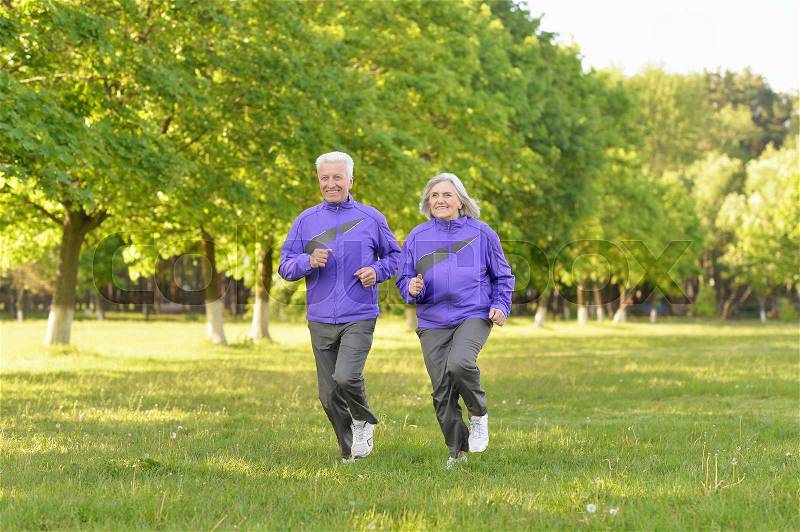 Happy fit senior couple jogging in park, stock photo