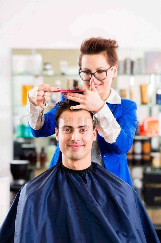 Female coiffeur cutting men hair in hairdresser shop, stock photo