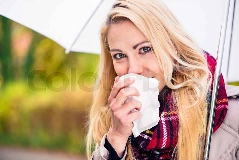 Woman having cold or flu due to bad autumn weather, stock photo