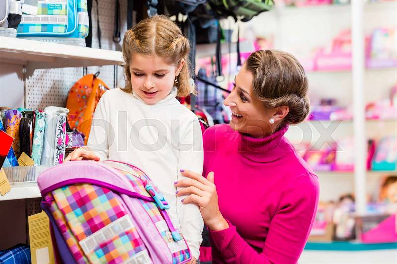 Mother and kid becoming a student buying school satchel or bag in store, stock photo