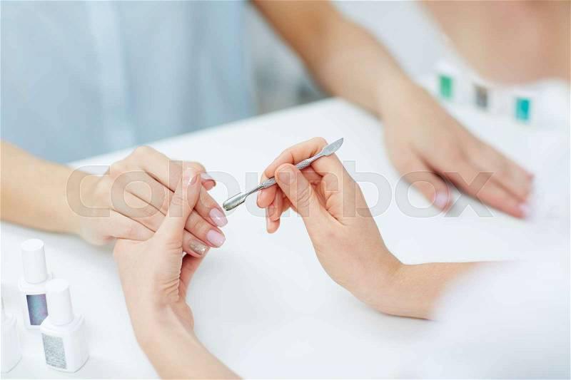 Woman hands in a nail salon receiving a manicure by a beautician, stock photo