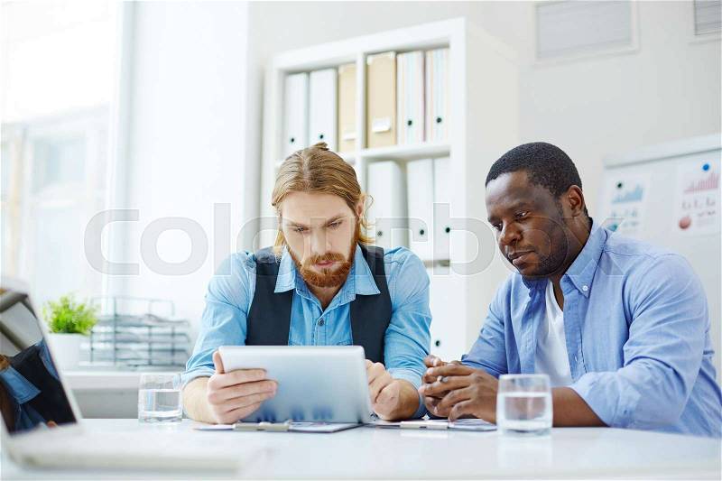 Two co-workers watching presentation on tablet pc, stock photo