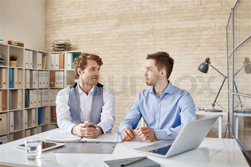 Two business people sitting at desk working in team together, stock photo