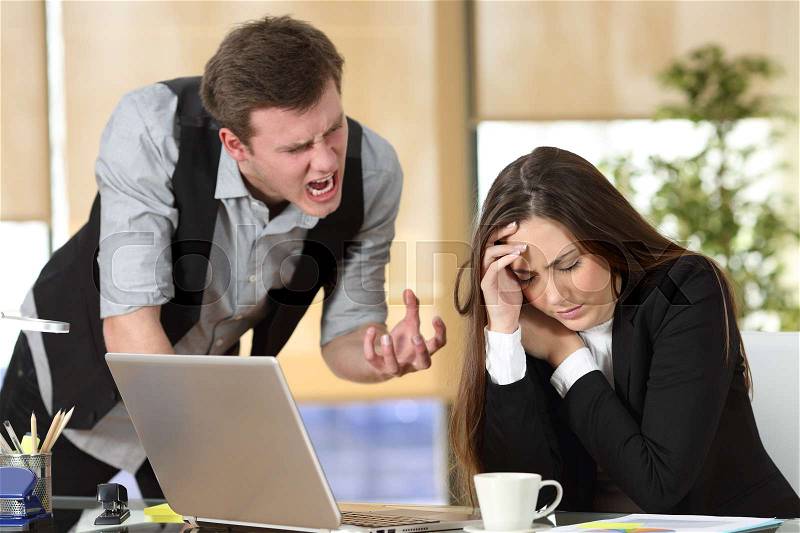 Bullying with an out of control boss shouting to a stressed employee in a desktop at office interior, stock photo