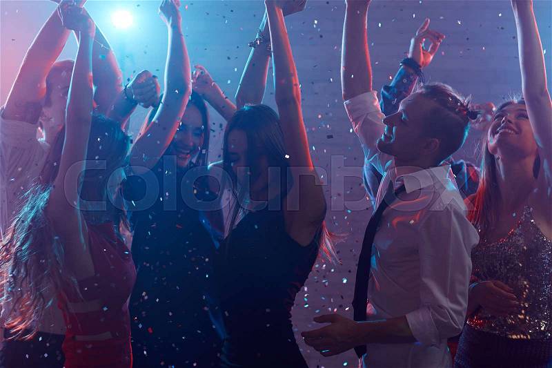 Crowd of ecstatic people dancing in night club, stock photo