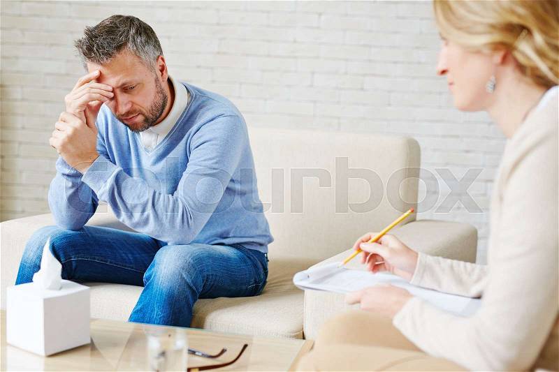 Sad man visiting his psychologist, stock photo