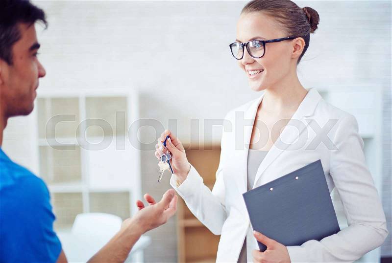 Smiling broker giving keys to man from new house, stock photo