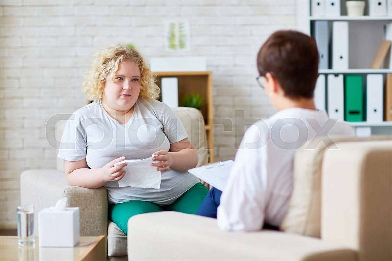 Young woman with overweight sharing her problem with psychologist, stock photo