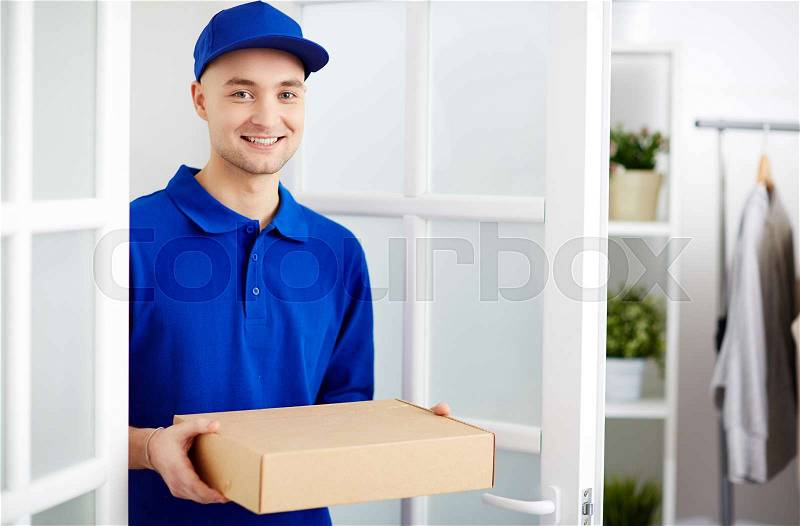 Portrait of deliveryman carrying a cardboard parcel box, stock photo