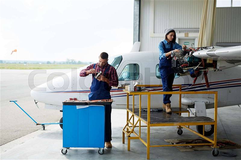 Team of aircraft engineers repairing parts of jet, stock photo