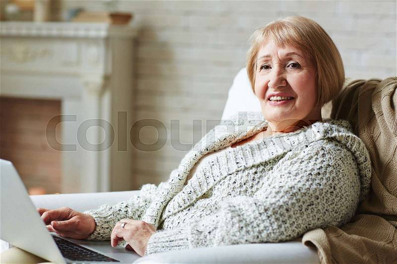 Happy woman with laptop networking at home, stock photo