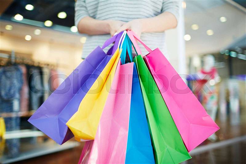 Multi-color paperbags held by young modern shopper, stock photo
