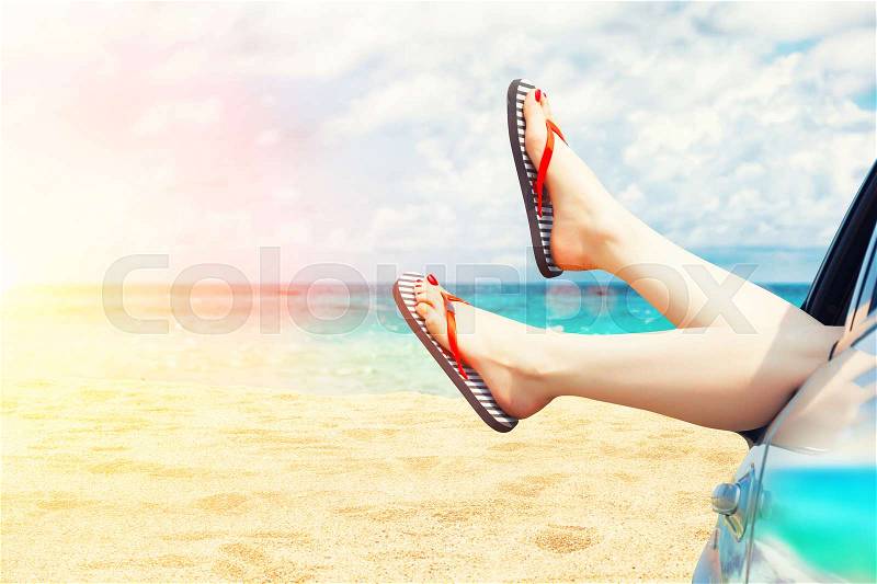 Female legs dangling from the open car window in the shales, stock photo