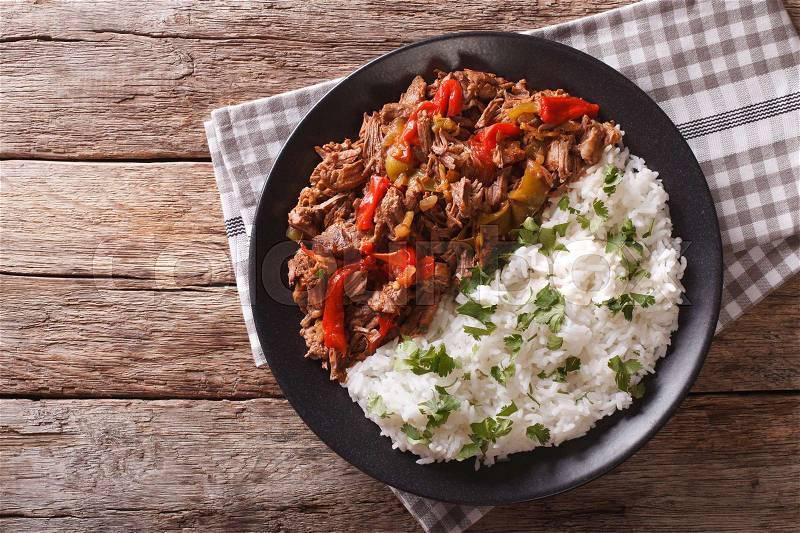 Ropa vieja: beef stew in tomato sauce with vegetables and rice garnish on a plate close-up. horizontal view from above , stock photo