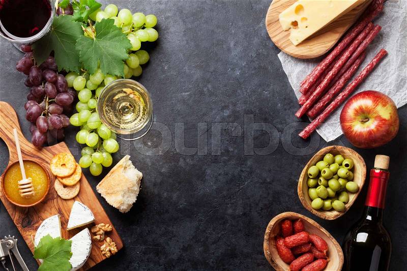 Red and white wine, grape, cheese and sausages on stone table. Top view with copy space, stock photo