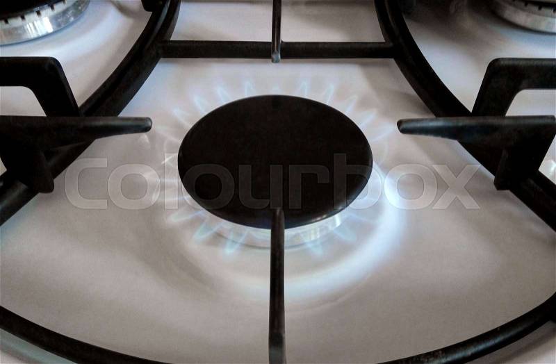Close-up of gas stove burner with blue gas flames, stock photo