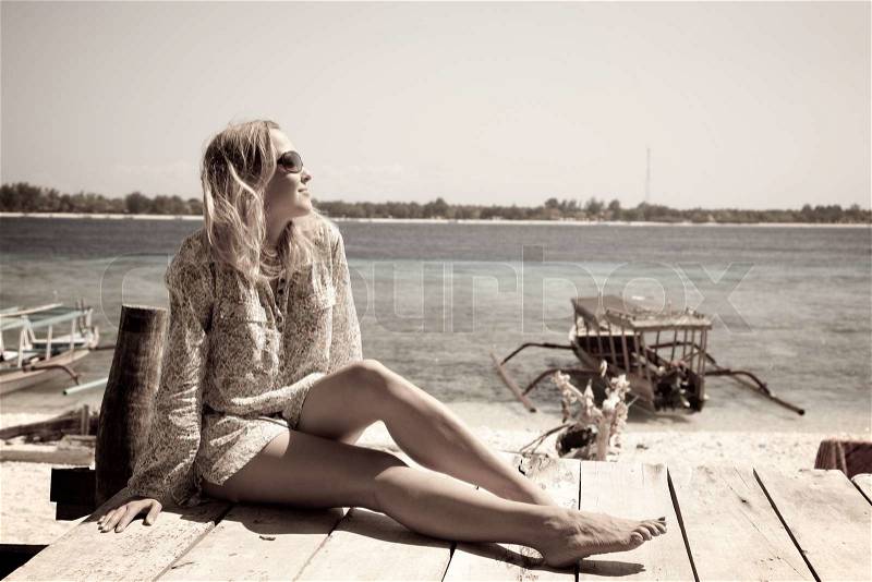 Woman laying at the wooden deck along the beach, stock photo