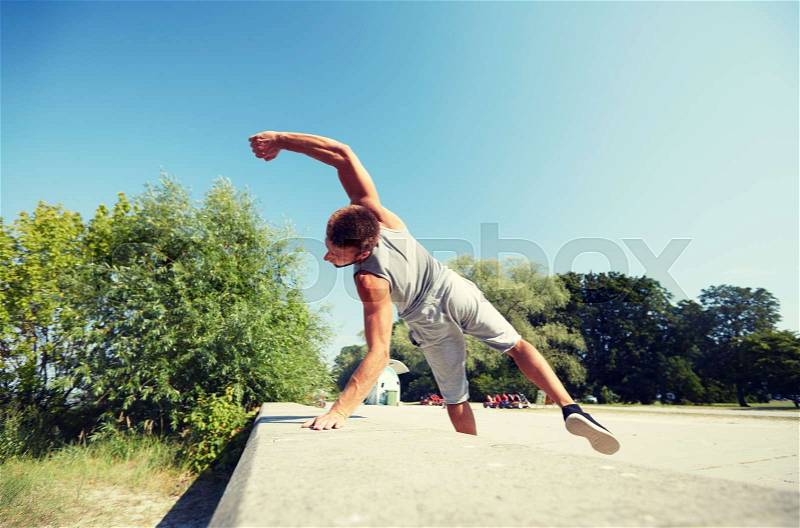 Fitness, sport, parkour and people concept - young man jumping in summer park, stock photo