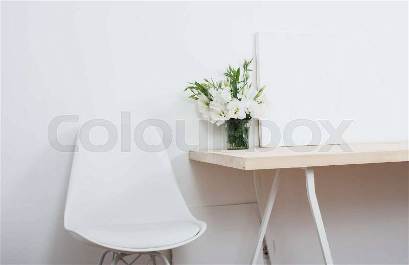 White scandinavian interior decor closeup: empty walls, designer chair, table and natural flowers, stock photo
