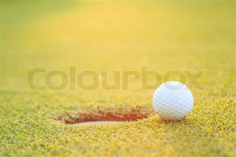 Close up golf ball on lip of cup in course, stock photo